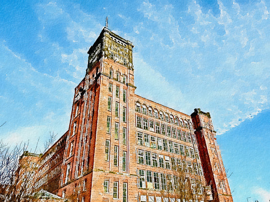 Tall brick mill building with a clock tower against a blue sky